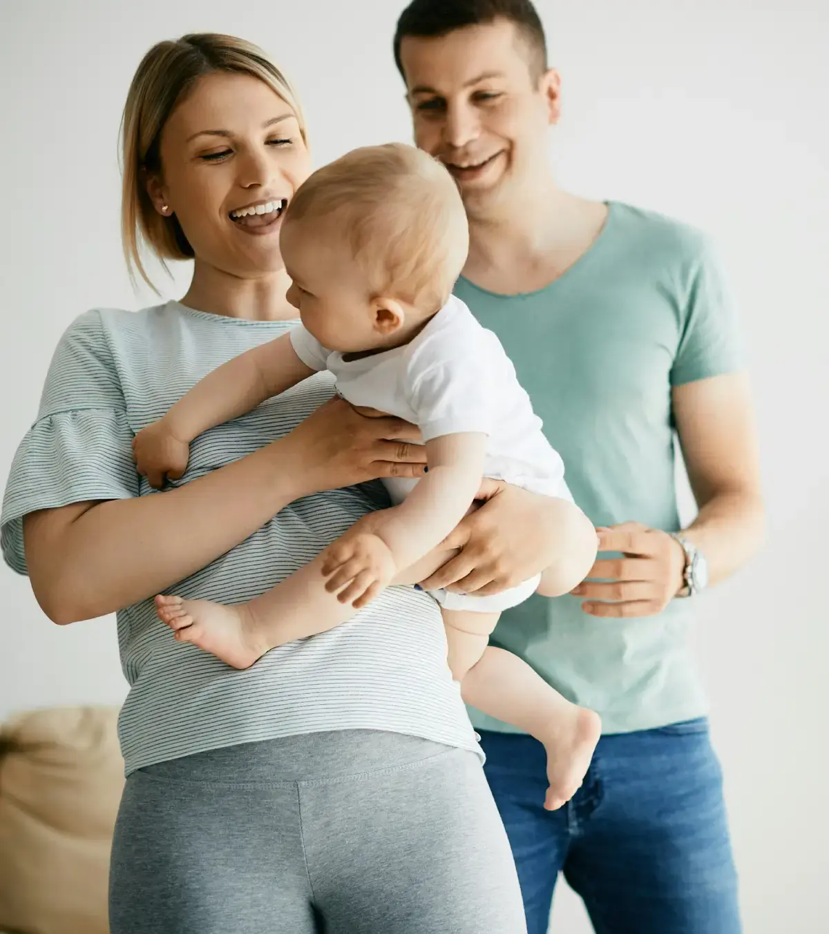 Mother holding her baby with the father in the background.