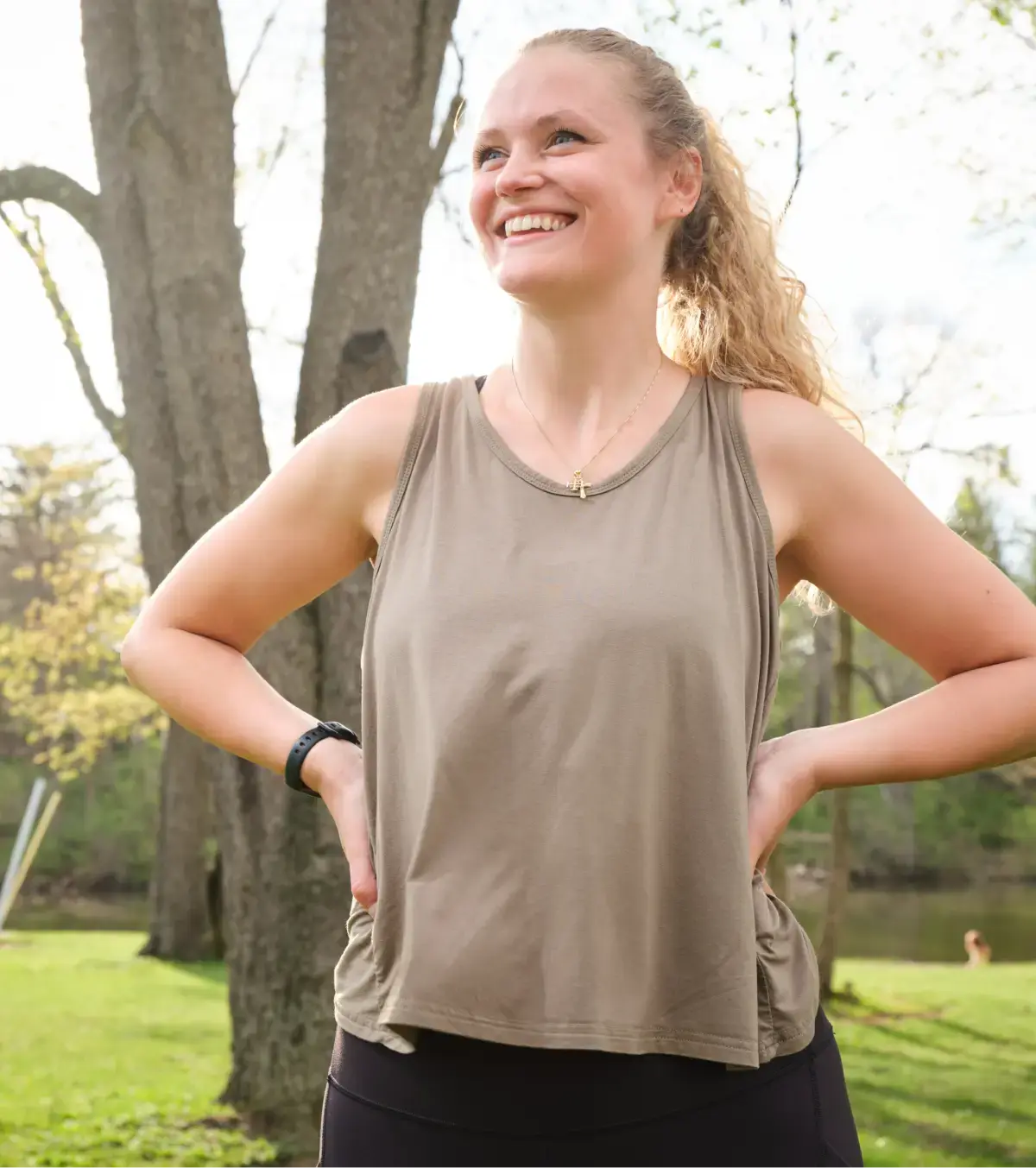 Smiling woman standing outside in a park.