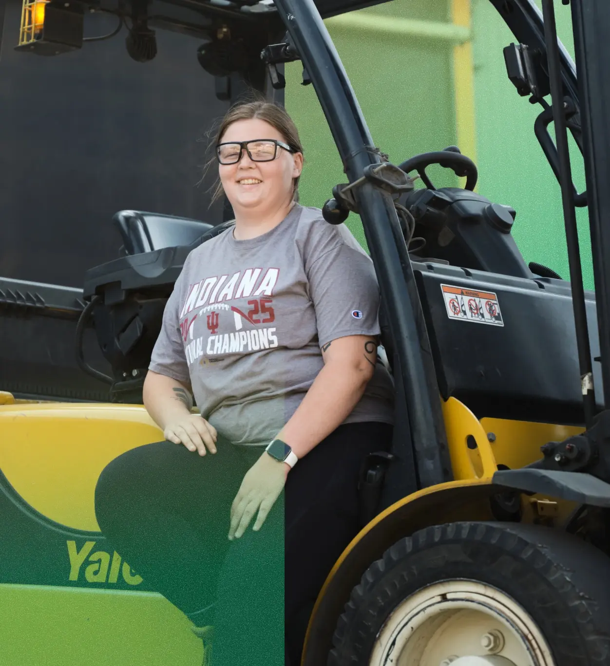 Female employee sitting on the side of a tractor.
