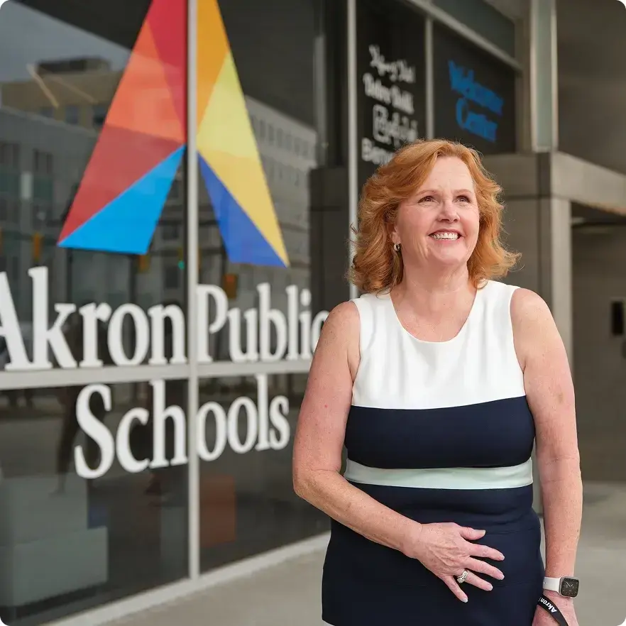 Akron Public School teacher standing in front of the school sign. 