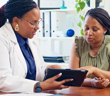 A provider in a lab coat reviews care data on a tablet with a member, collaborating on personalized health outcomes—a glimpse into the future of preventive care, where partnerships like these are making grand strides toward healthier lives.