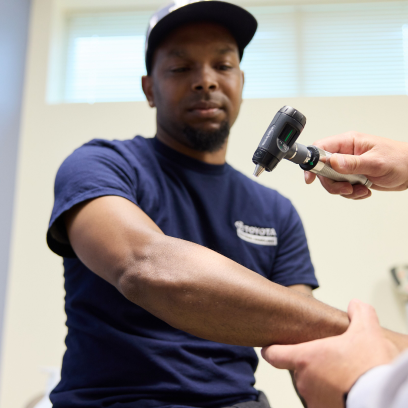 Union worker receiving a forearm exam during an occupational health visit, representing healthcare challenges for union members and the need for accessible, coordinated care.