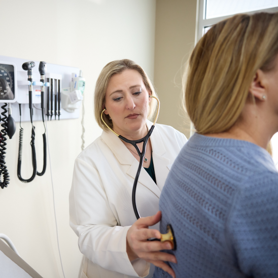 Advanced primary care physician uses a stethoscope to examine a patient, supporting specialty care referral management, care coordination, and care navigation at a Marathon Health clinic