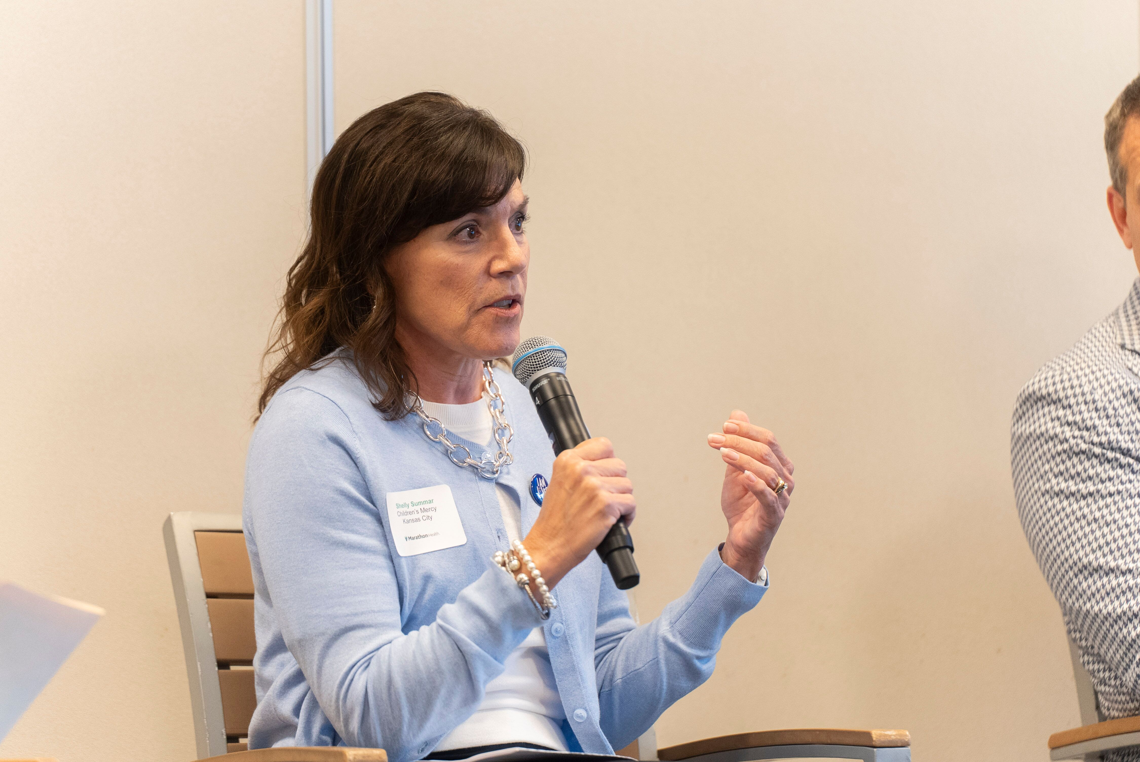 Shelly Summar speaking into microphone at Marathon Health Kansas City roundtable.