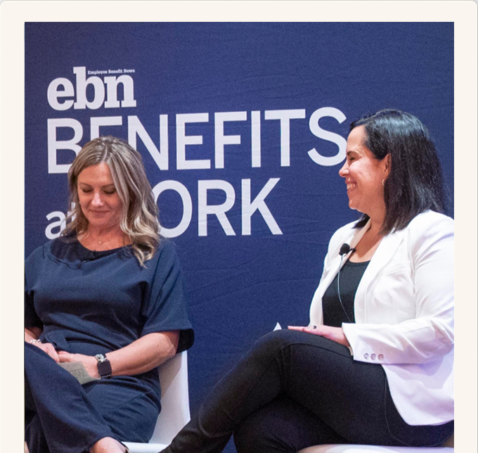 Two women sit on stage in conversation at the EBN Benefits at Work event, in front of a navy backdrop with the event logo.