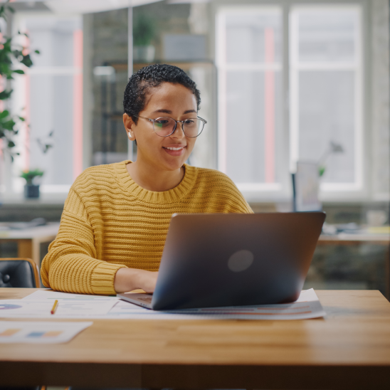 Woman reviewing charts and researching on a laptop while planning an employee health center.