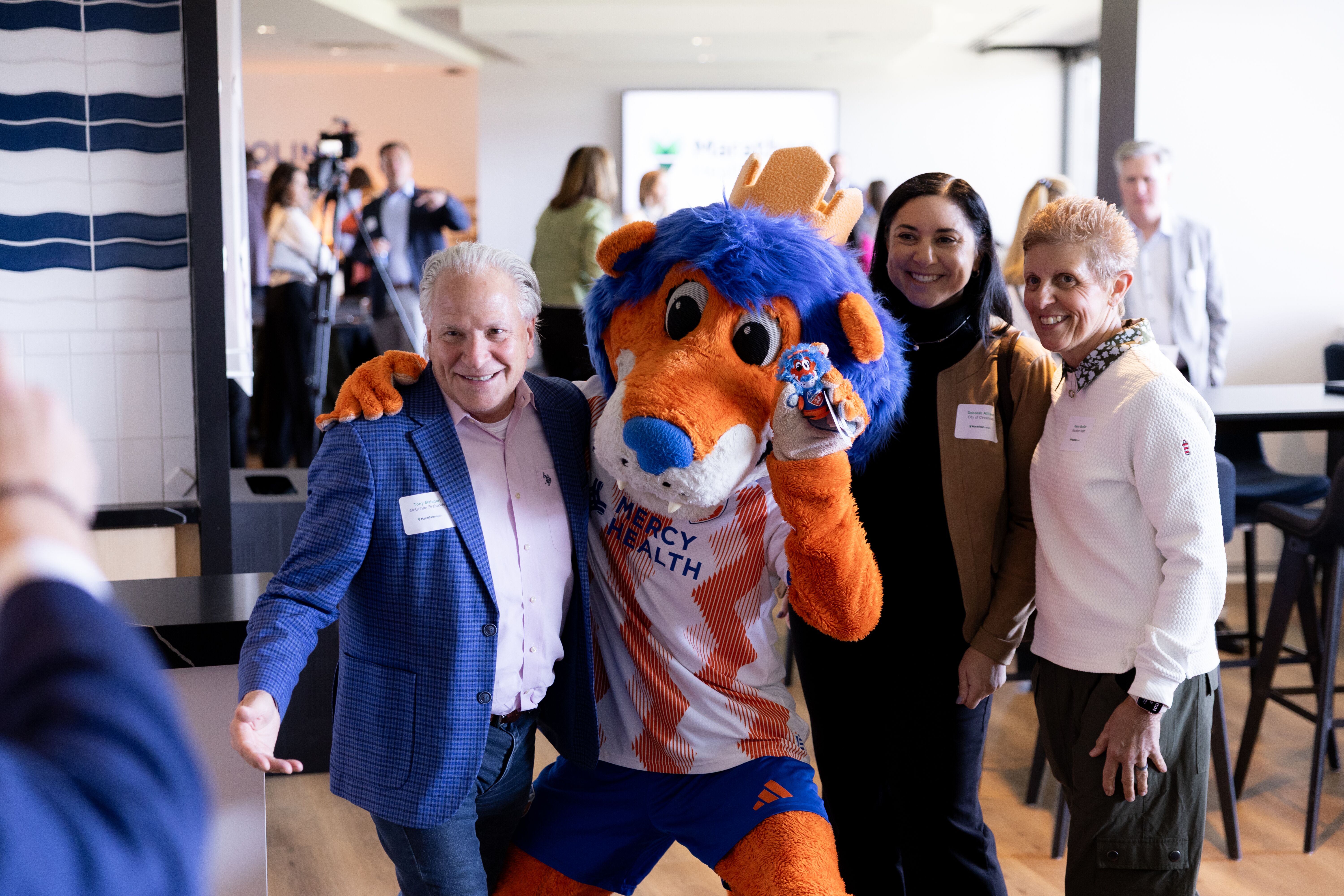 Attendees pose with the Mercy Health mascot at the TQL Stadium event.