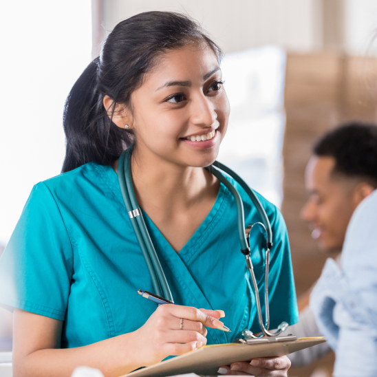 Smiling healthcare provider reviewing patient notes on a clipboard.