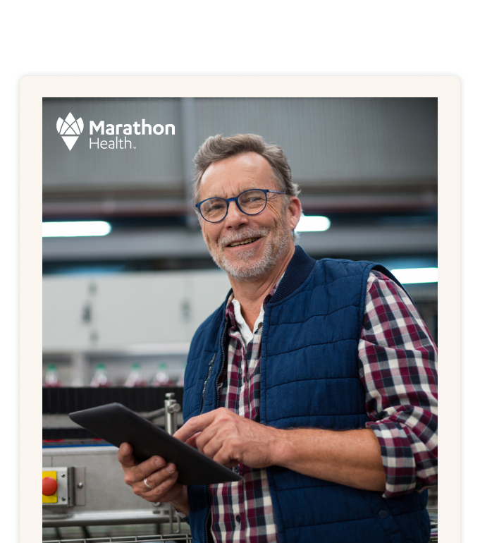 A smiling worker in glasses and a vest with a tablet at a production line