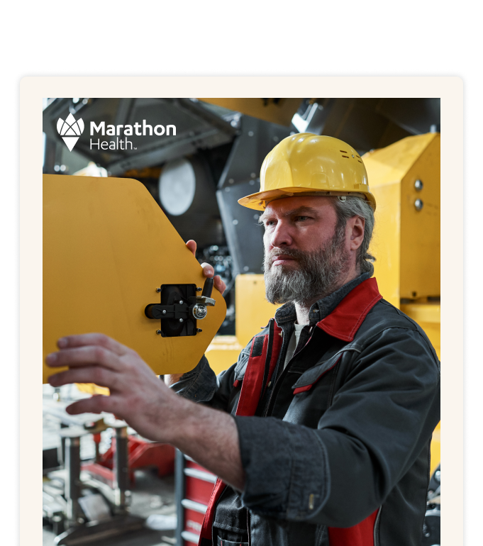 A worker in a yellow hard hat adjusting a panel on yellow machinery.